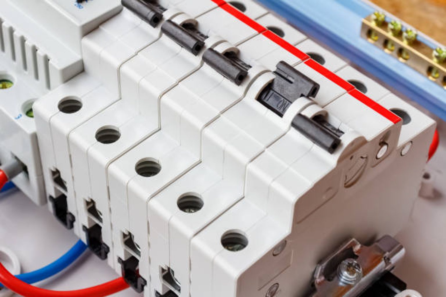 Installed automatic circuit breakers on DIN rail in white plastic mounting box closeup
